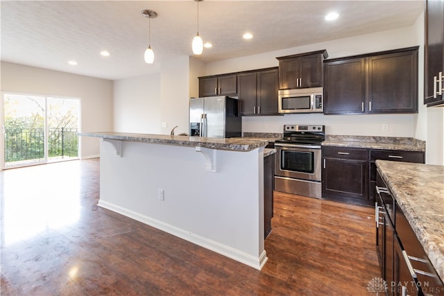 kitchen featuring pendant lighting, dark hardwood / wood-style flooring, a breakfast bar, and stainless steel appliances