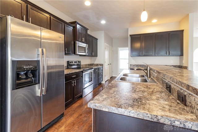 kitchen with dark brown cabinetry, sink, dark wood-type flooring, pendant lighting, and appliances with stainless steel finishes