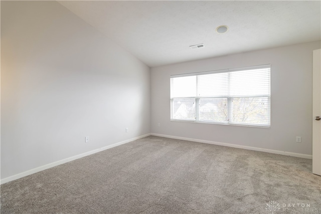 carpeted empty room with vaulted ceiling