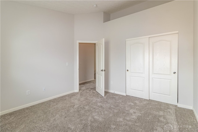 unfurnished bedroom featuring light carpet and a closet