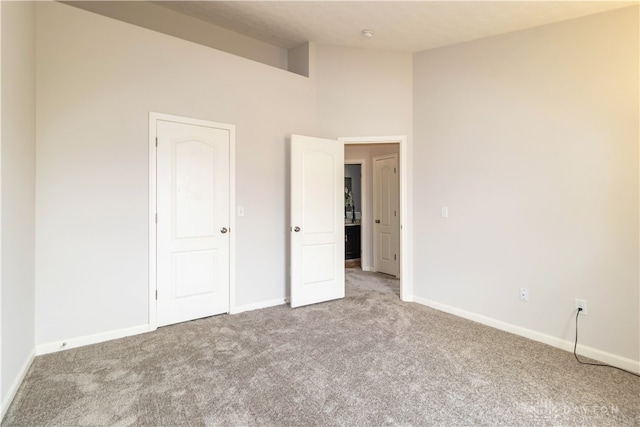 unfurnished bedroom with light carpet and a high ceiling