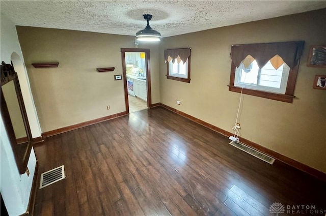 spare room with dark hardwood / wood-style floors and a textured ceiling