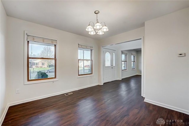 foyer entrance with dark wood-type flooring and a notable chandelier