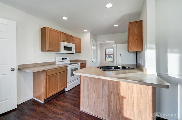 kitchen featuring white appliances, dark hardwood / wood-style flooring, kitchen peninsula, and sink