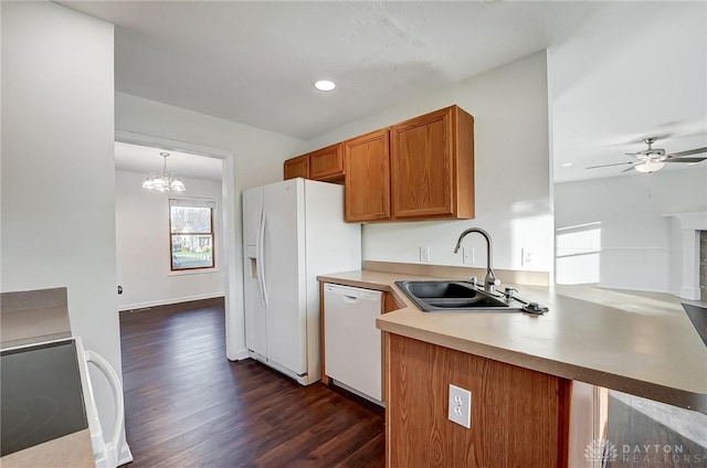 kitchen featuring decorative light fixtures, sink, dark hardwood / wood-style flooring, kitchen peninsula, and white appliances