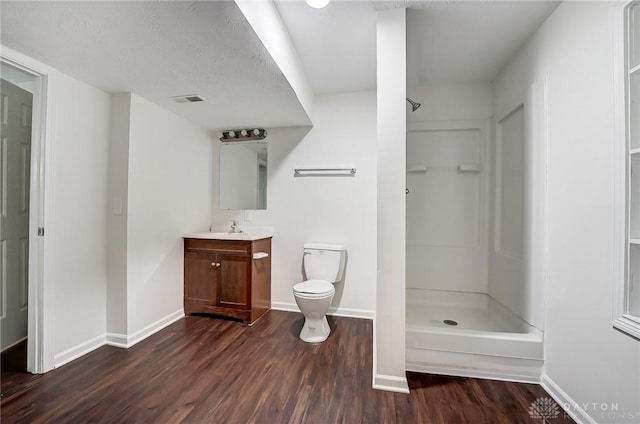 bathroom featuring vanity, hardwood / wood-style flooring, toilet, and a shower