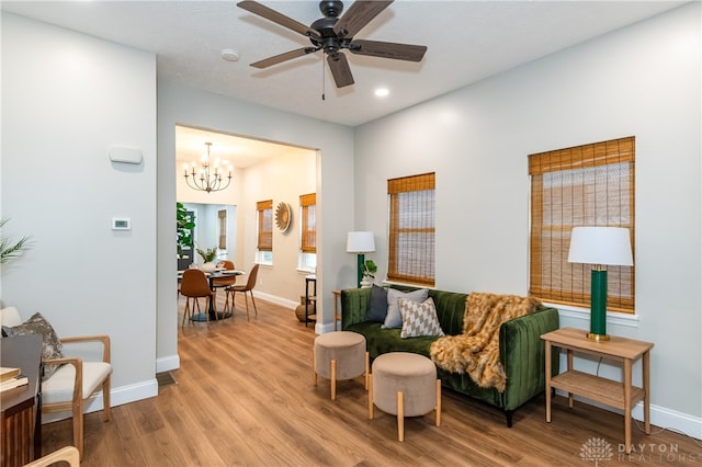 living room featuring light hardwood / wood-style floors and ceiling fan with notable chandelier