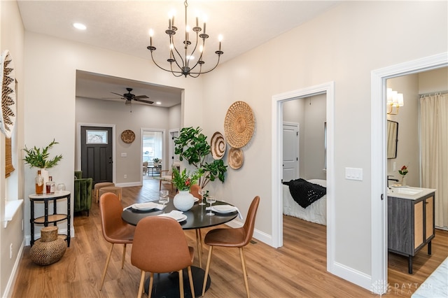 dining room featuring hardwood / wood-style flooring, ceiling fan with notable chandelier, and sink