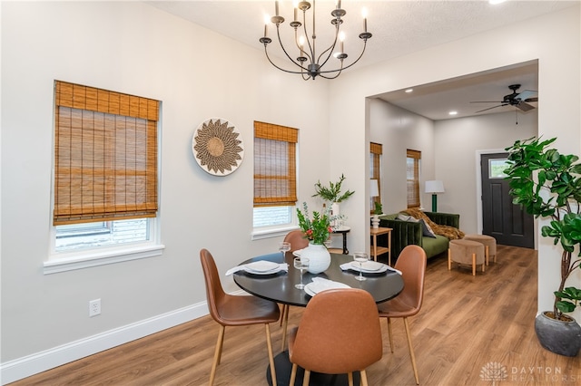 dining space featuring hardwood / wood-style floors, a healthy amount of sunlight, and ceiling fan with notable chandelier