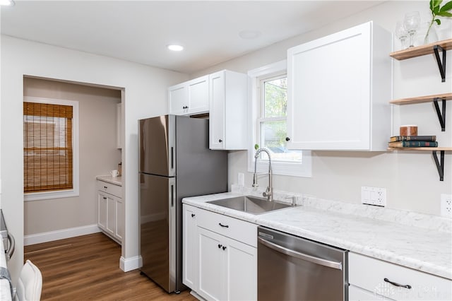 kitchen with sink, dark hardwood / wood-style floors, appliances with stainless steel finishes, light stone counters, and white cabinetry