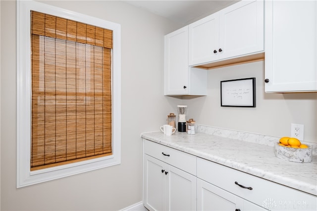 kitchen featuring white cabinetry and light stone counters