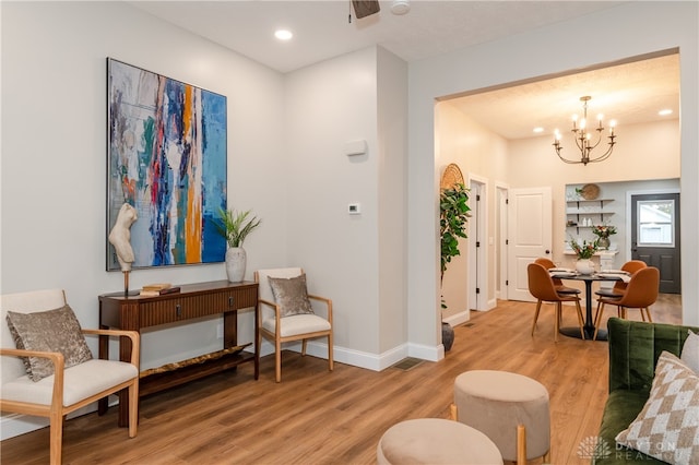 sitting room with light hardwood / wood-style flooring and an inviting chandelier