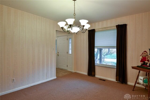 carpeted empty room with a chandelier