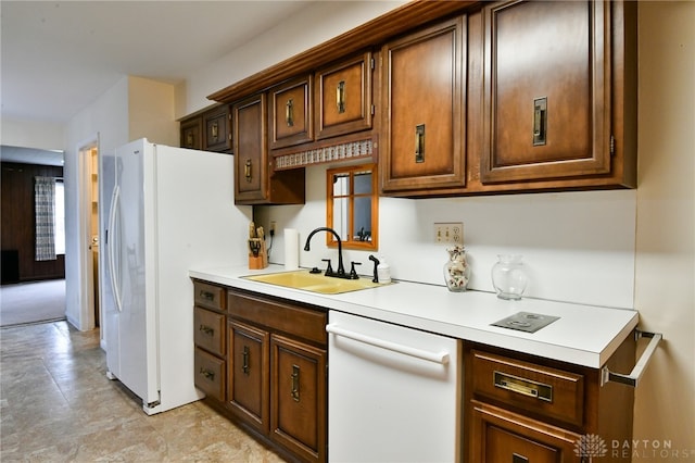 kitchen with white appliances, dark brown cabinetry, and sink