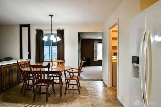 dining space featuring a healthy amount of sunlight, washer / dryer, and an inviting chandelier