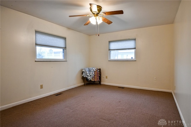 carpeted spare room featuring ceiling fan and a healthy amount of sunlight