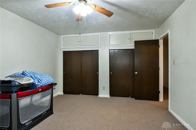 carpeted bedroom with ceiling fan and two closets