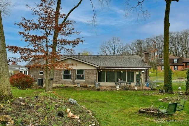 5331 Birchbend Ct, Dayton, OH 45415 - back of property featuring brick siding, a shingled roof, a sunroom, a yard, and a chimney
