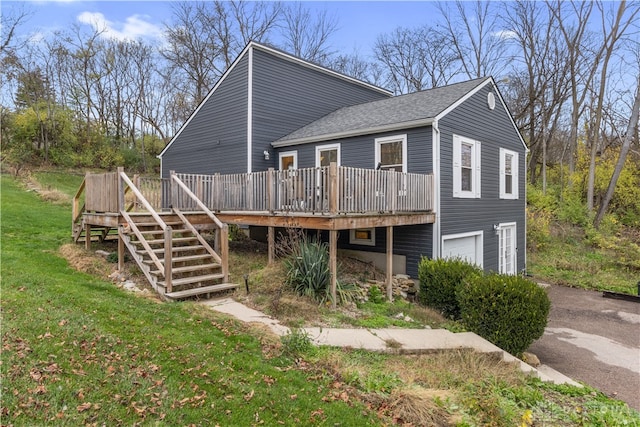 rear view of property with a deck, a garage, and a lawn