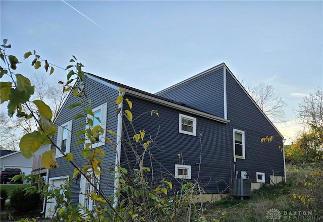 property exterior at dusk featuring central AC unit and a garage