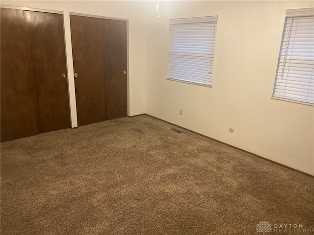 unfurnished bedroom featuring carpet floors and multiple closets