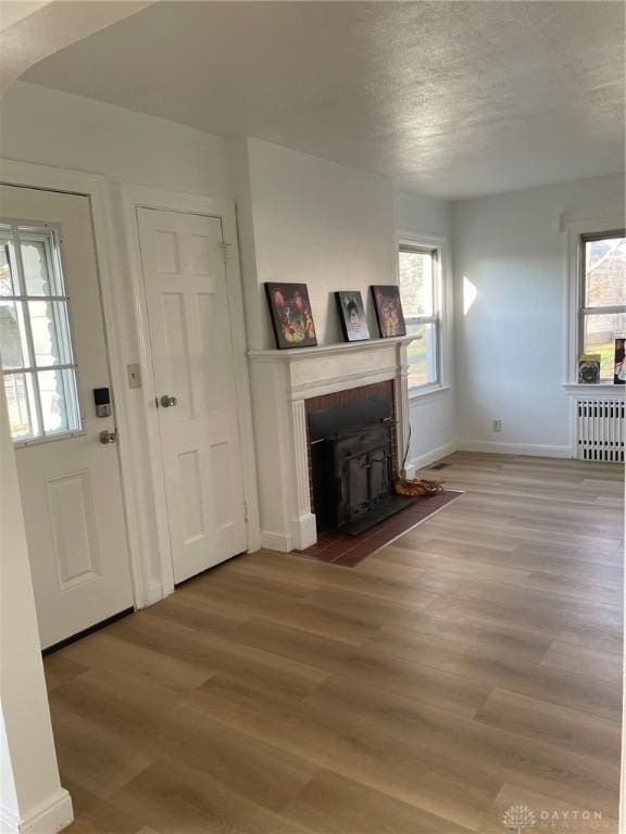 unfurnished living room with radiator, a wood stove, a textured ceiling, and hardwood / wood-style flooring