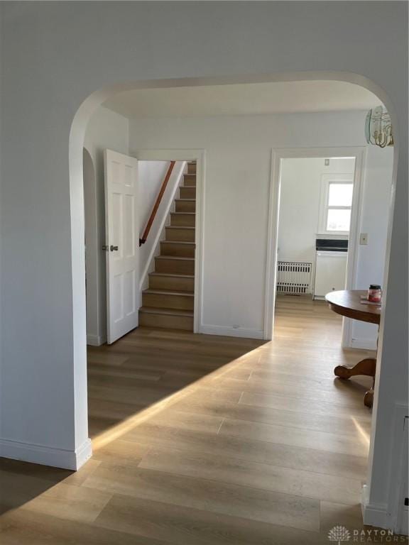 hallway with dark hardwood / wood-style flooring, radiator heating unit, and an inviting chandelier