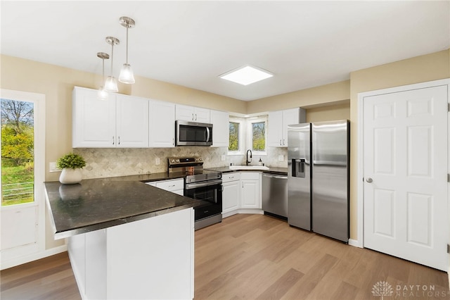 kitchen featuring kitchen peninsula, hanging light fixtures, a healthy amount of sunlight, and appliances with stainless steel finishes