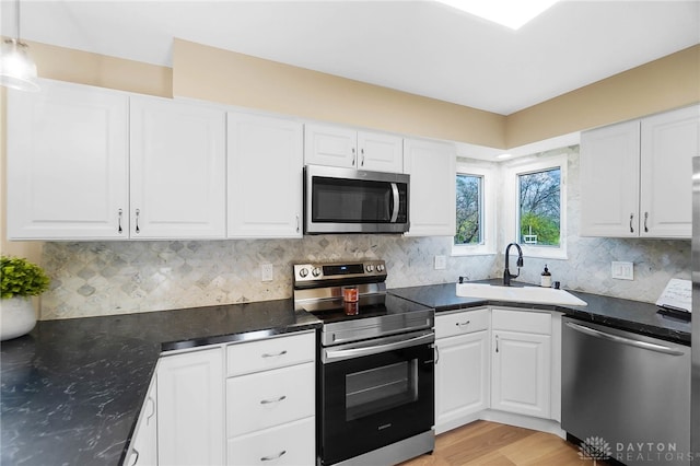 kitchen with white cabinets, sink, light wood-type flooring, decorative light fixtures, and stainless steel appliances