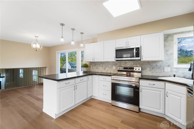 kitchen featuring kitchen peninsula, white cabinetry, stainless steel appliances, and decorative light fixtures