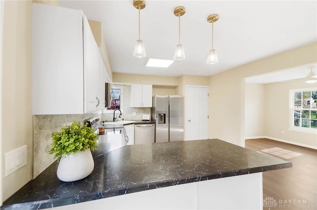 kitchen with pendant lighting, white cabinets, dark hardwood / wood-style floors, tasteful backsplash, and stainless steel appliances