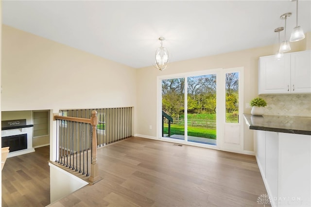 unfurnished dining area with an inviting chandelier and hardwood / wood-style flooring