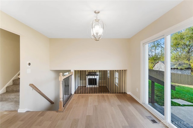 unfurnished living room featuring a chandelier, light wood-type flooring, and a water view