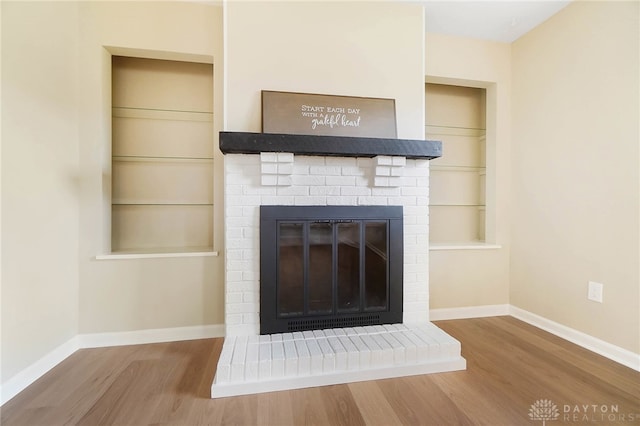 interior details featuring hardwood / wood-style flooring, built in shelves, and a brick fireplace