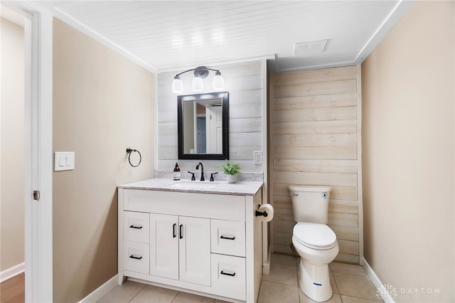 bathroom with toilet, vanity, tile patterned floors, and wooden walls