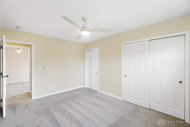 unfurnished bedroom with ceiling fan, light carpet, and two closets