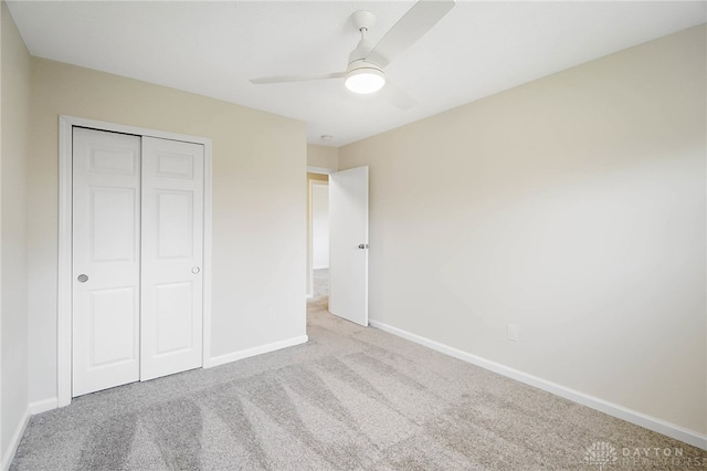 unfurnished bedroom with ceiling fan, light colored carpet, and a closet