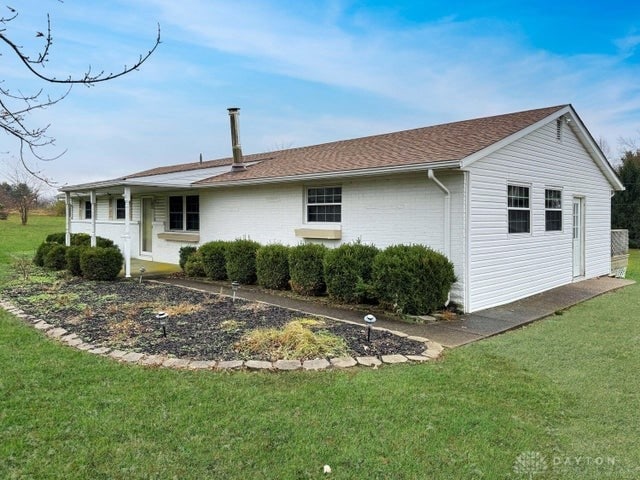 rear view of property featuring a lawn and covered porch