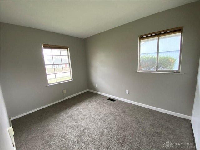 spare room featuring dark colored carpet