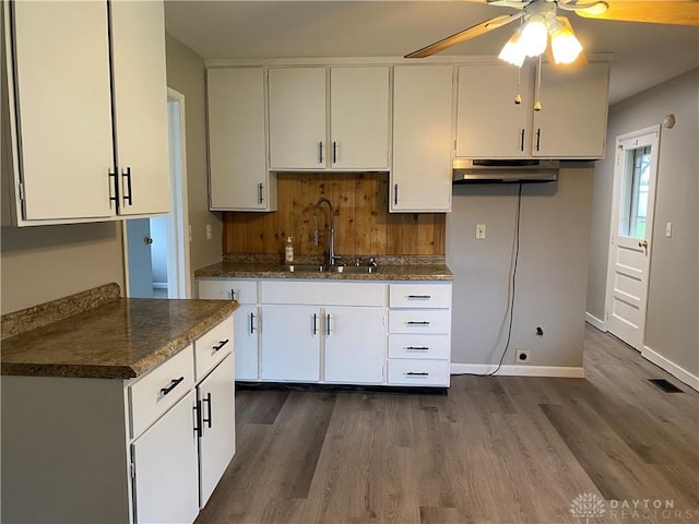 kitchen with sink, dark wood-type flooring, white cabinets, and ceiling fan