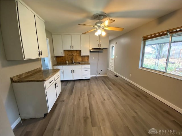 kitchen with dark wood-type flooring, sink, white cabinetry, tasteful backsplash, and ceiling fan