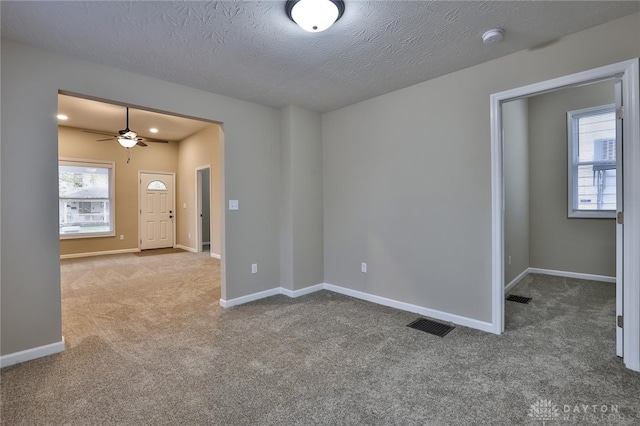 carpeted empty room with ceiling fan and a textured ceiling