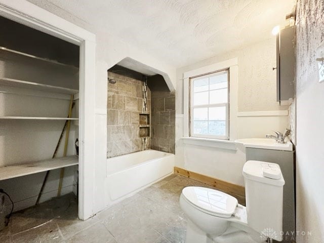 bathroom featuring toilet and tiled shower / bath