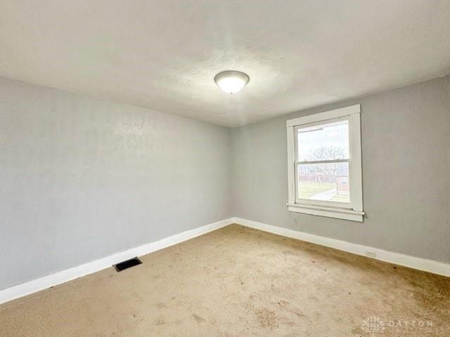 carpeted empty room featuring visible vents and baseboards