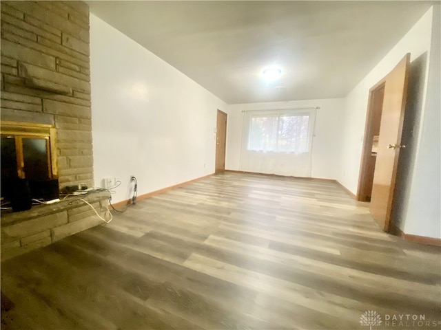 unfurnished living room featuring a stone fireplace and wood-type flooring