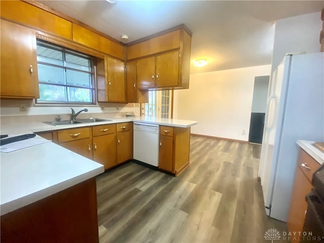 kitchen featuring kitchen peninsula, white appliances, hardwood / wood-style flooring, and sink