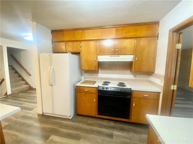 kitchen with dark wood-type flooring, black range with electric cooktop, white refrigerator, backsplash, and a textured ceiling