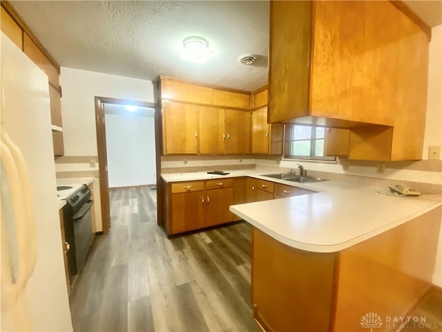 kitchen featuring electric range, sink, dark hardwood / wood-style floors, kitchen peninsula, and a textured ceiling