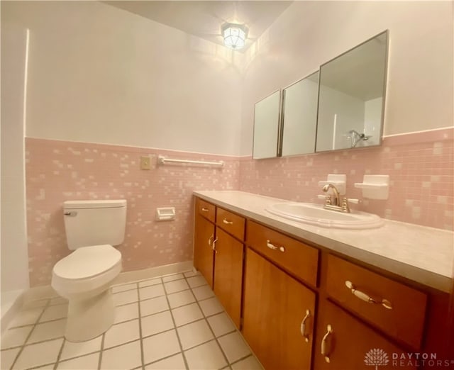 bathroom featuring tile patterned floors, vanity, toilet, and tile walls