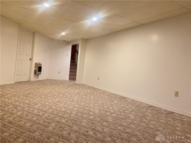 basement with carpet, a drop ceiling, and heating unit